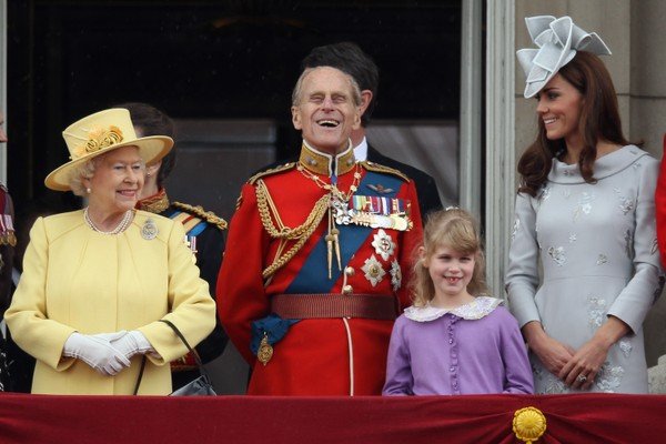 Na photography colorida, Louise (de roxo) aparece sorrindo perto dos avós, Elizabeth II e Philip, e proxima ate Kate